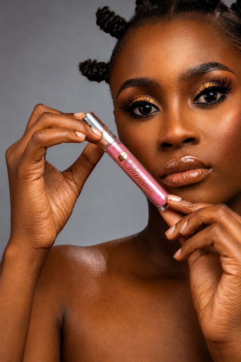 Model holding Ada shimmer gloss beside her face