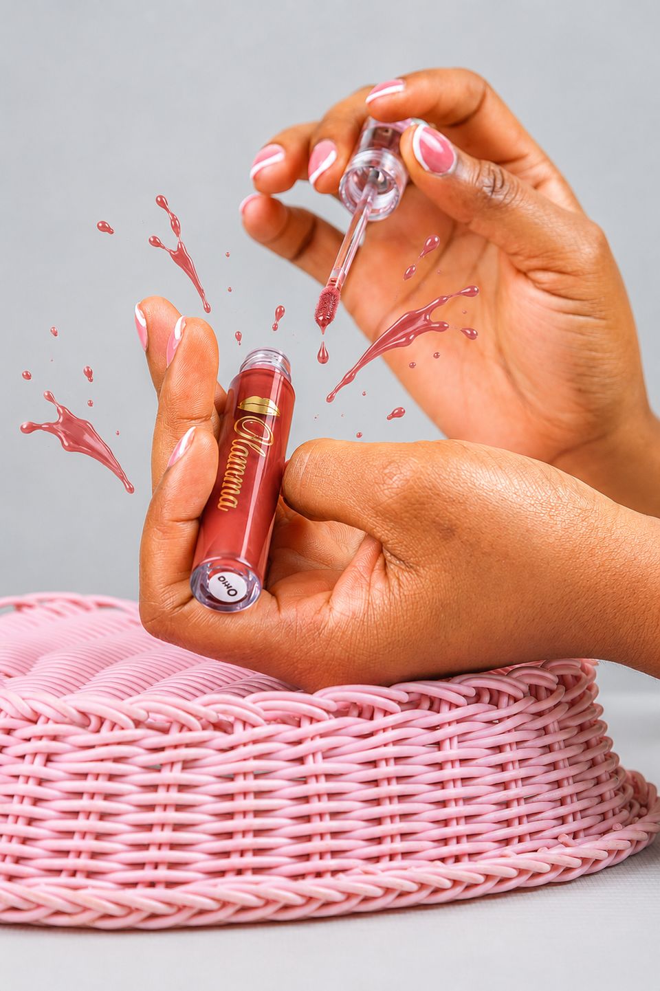 Ugo Peach Kiss red gloss dripping from the wand onto a pink basket