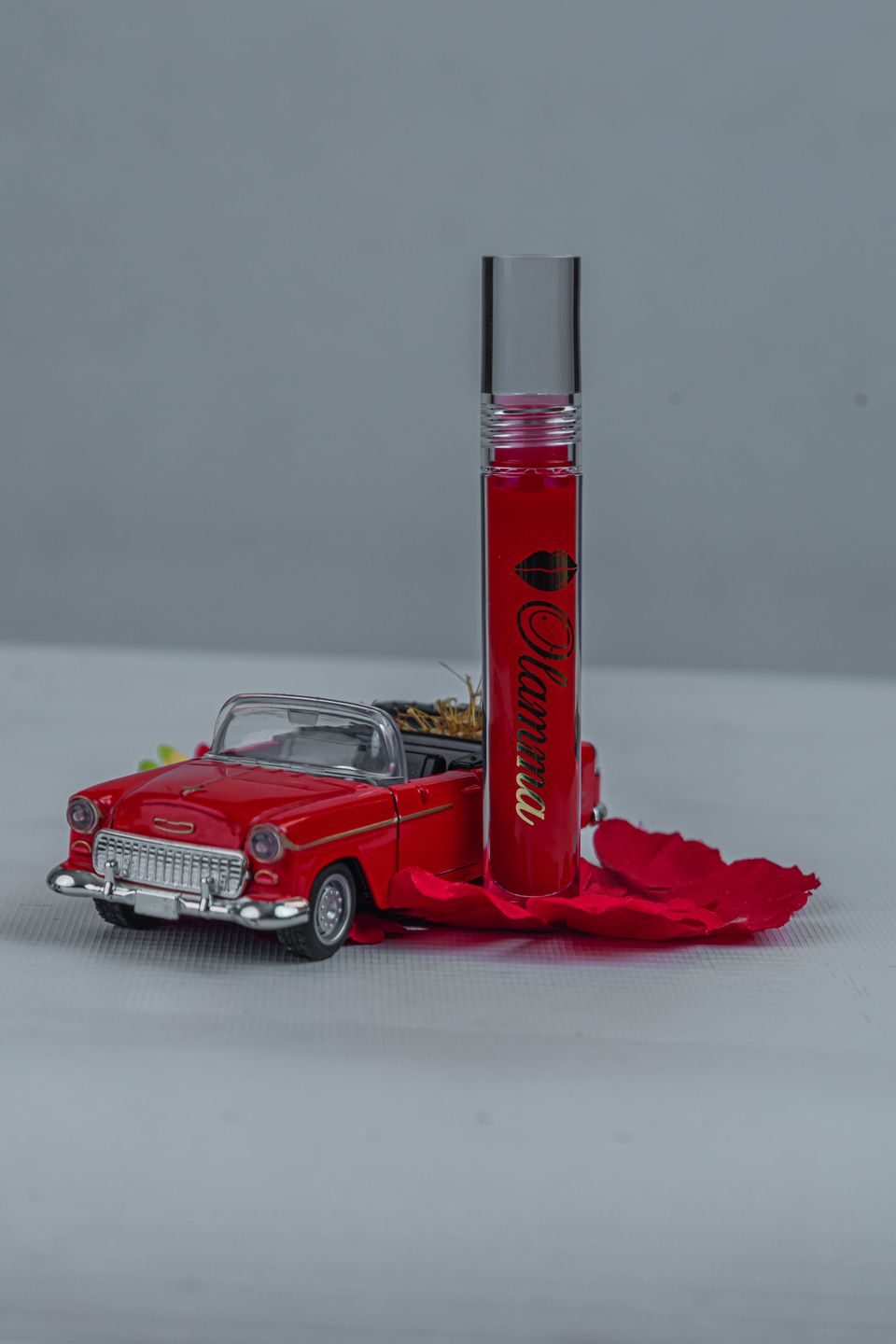 Red Ugo gloss standing beside a red toy convertible