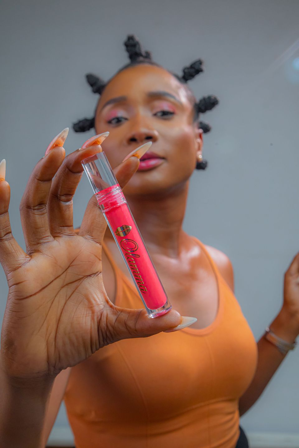 Woman holding a gloss tube towards the camera